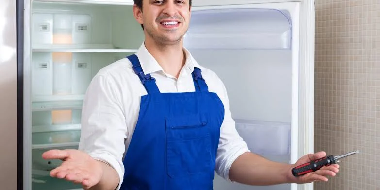 Appliance technician holding a screwdriver in front of a refrigerator