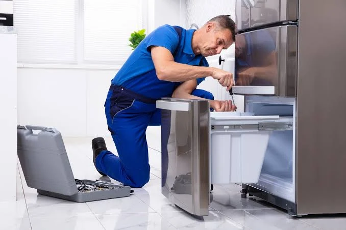 Technician servicing an open refrigerator drawer